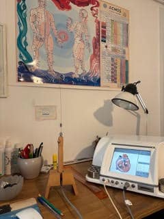 Bureau Acmos de bioénergie: écran cœur, pendule de mesure, flacons. Murs: posters Acmos "anatomie" et "Tableau de test".